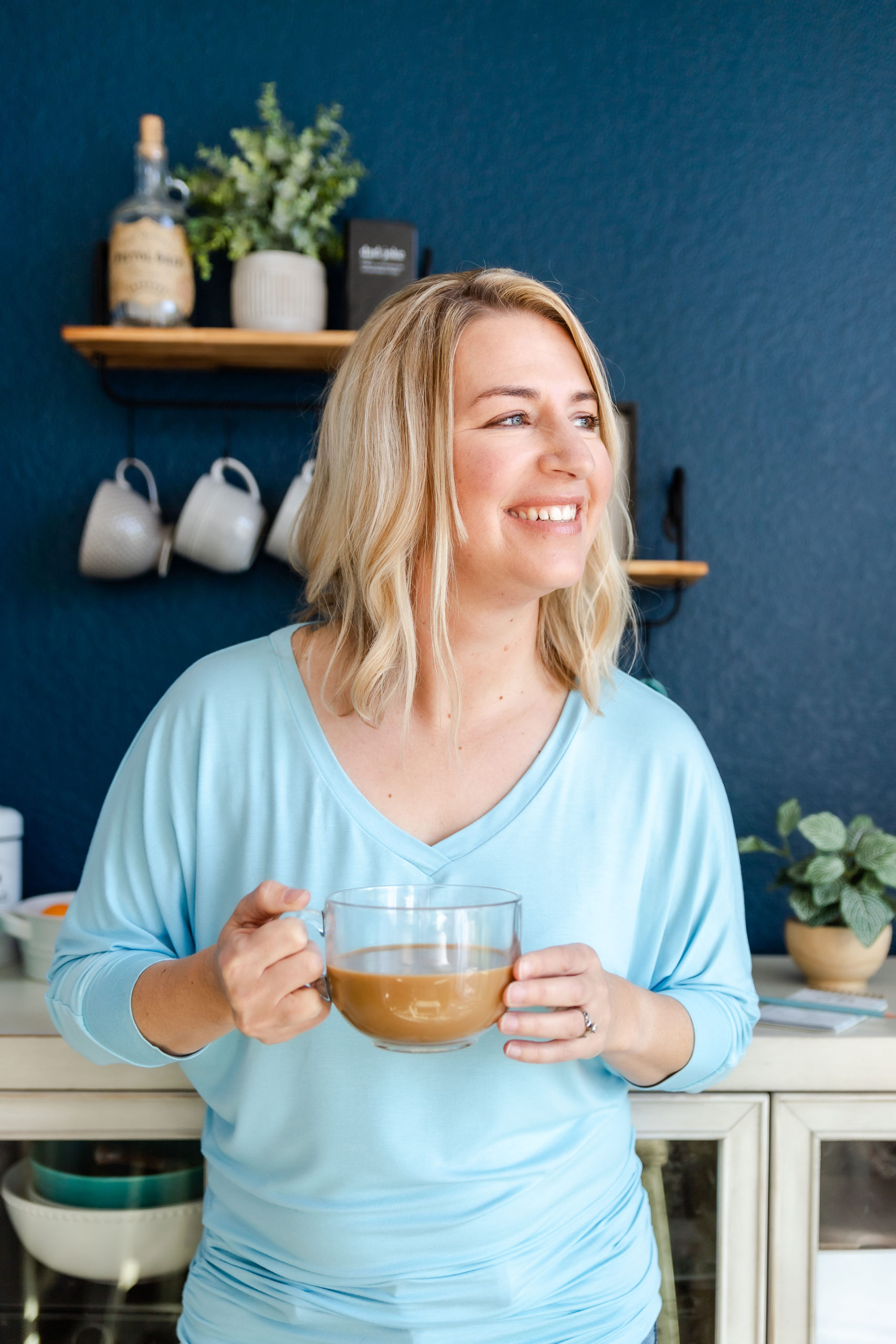 white-lady-with-blonde-hair-wearing-a-sky-blue-blouse-and-holding-a-glass-of-cofee