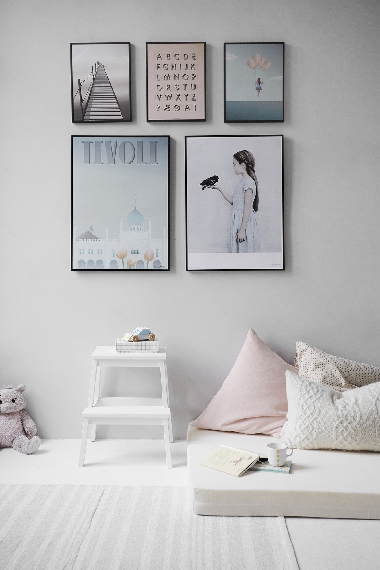 White-wall-with-five-wall-frame-and-bed-on-the-floor-with-cofee-on-a-book