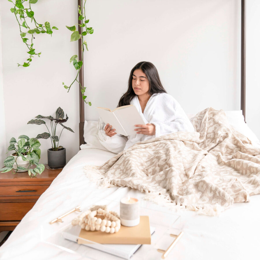 white-brunner-lady-wearing-a-bathrobe-on-a-white-bed-reading-a-book