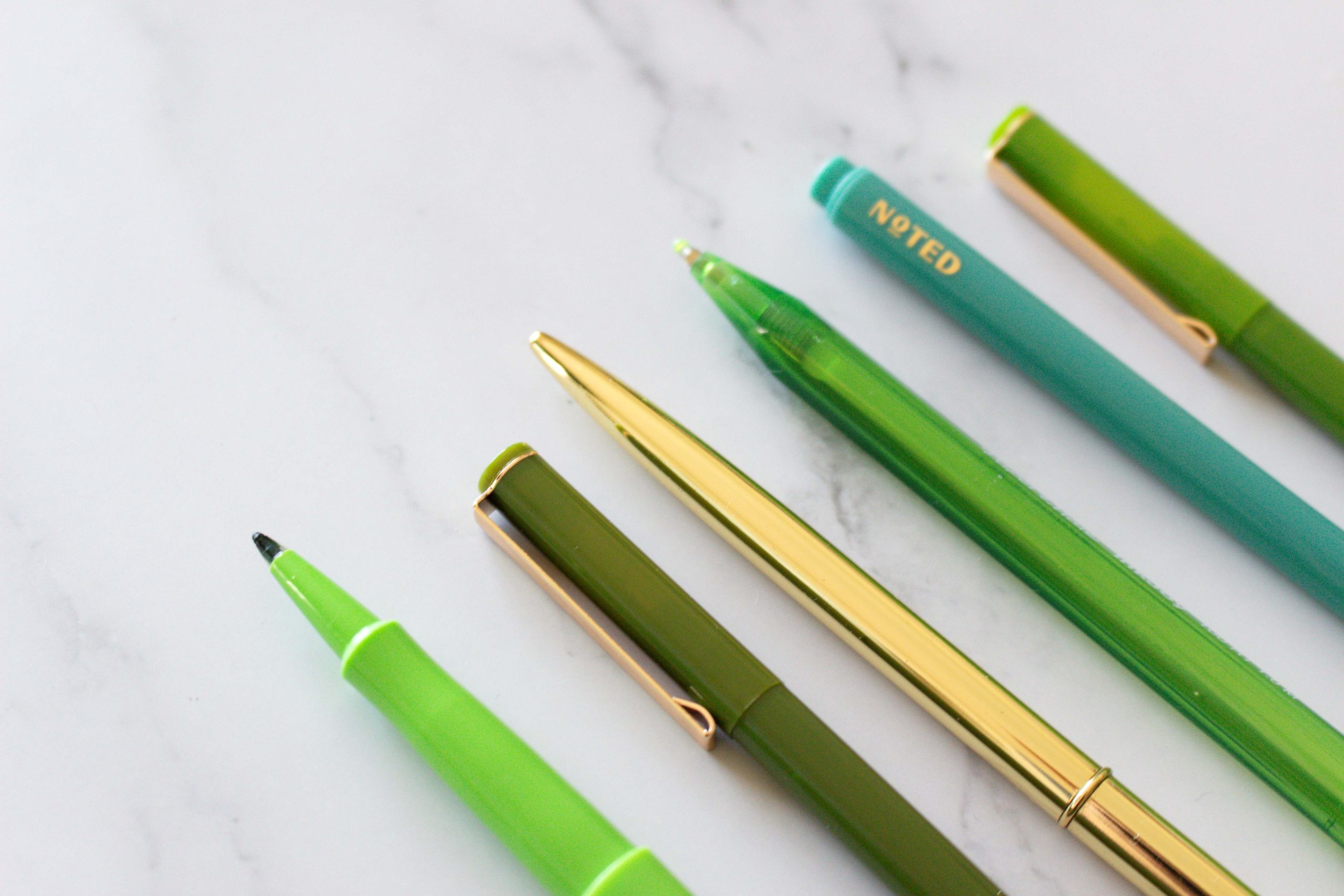 six pens with different shades of green colour