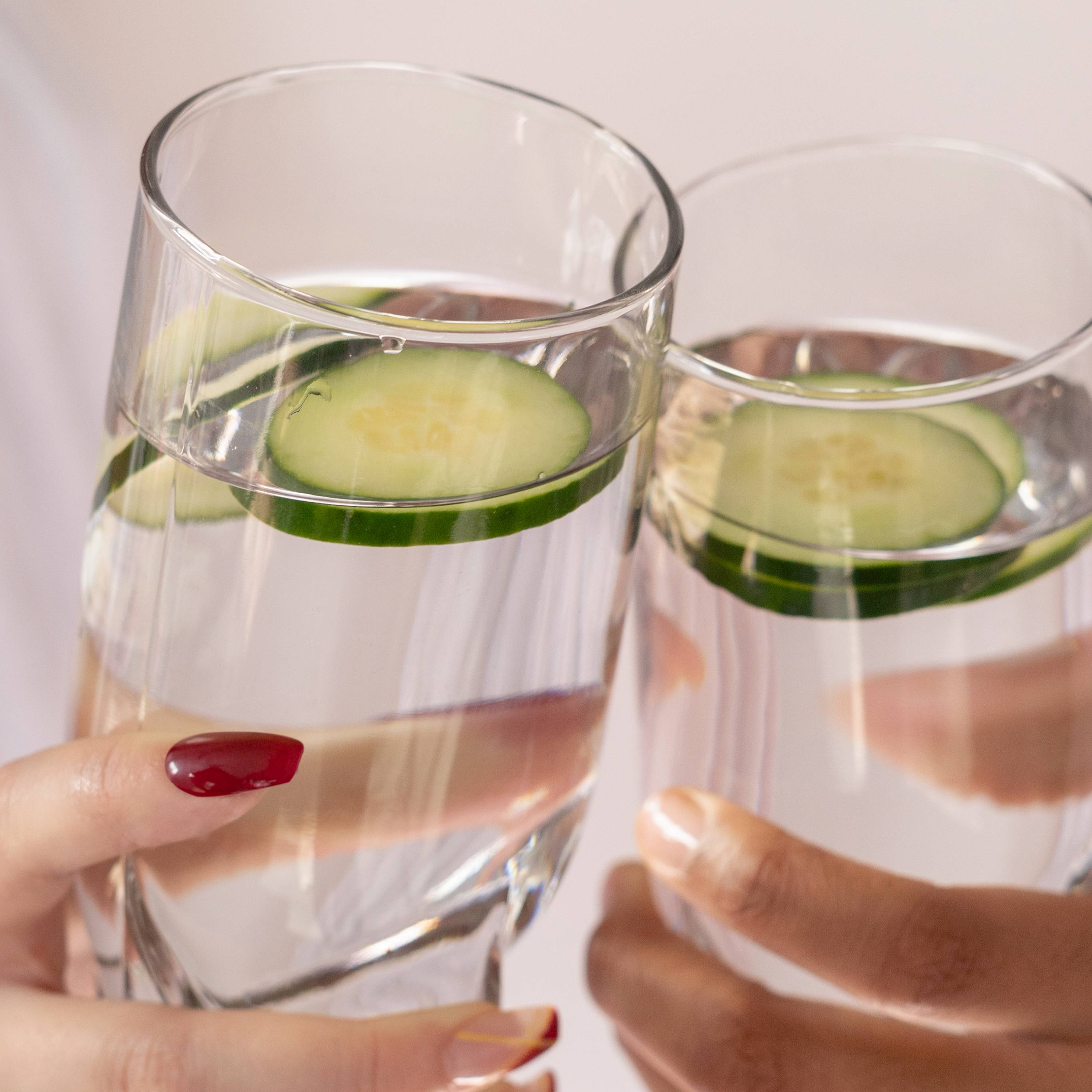 Water in two glass cups with cucumber slice on each.