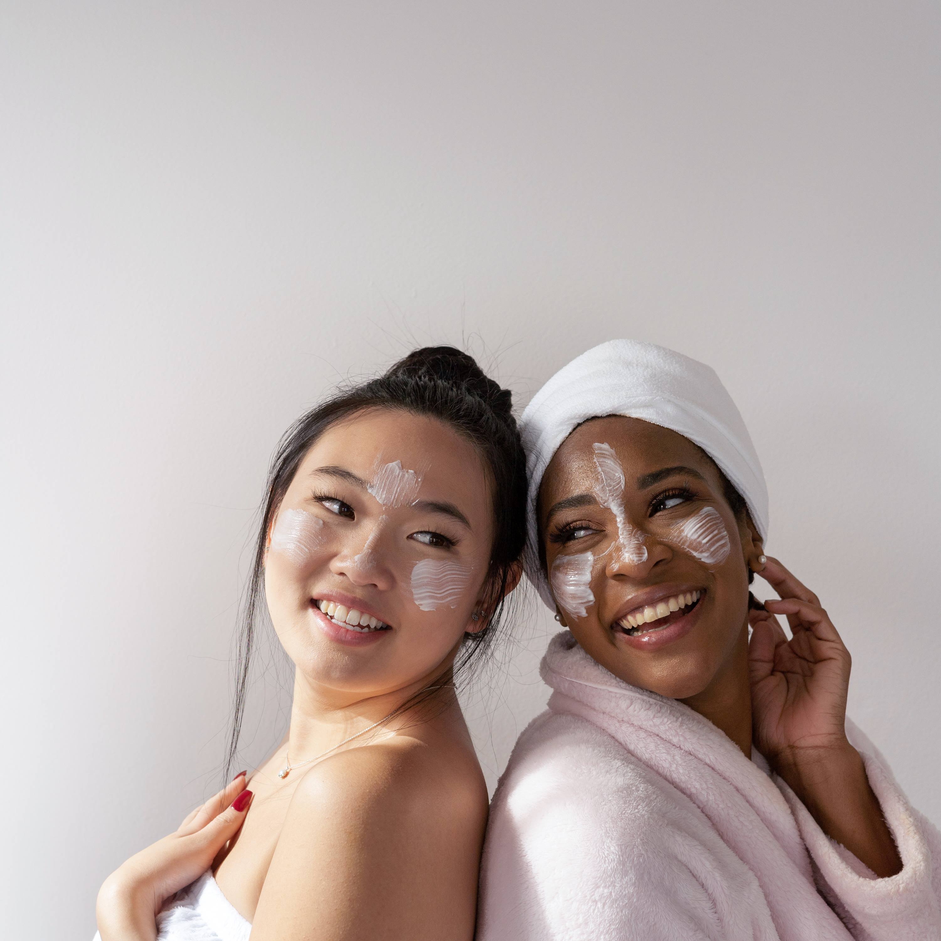 An Asian lady and a black lady having a spa moment with smiles on their faces