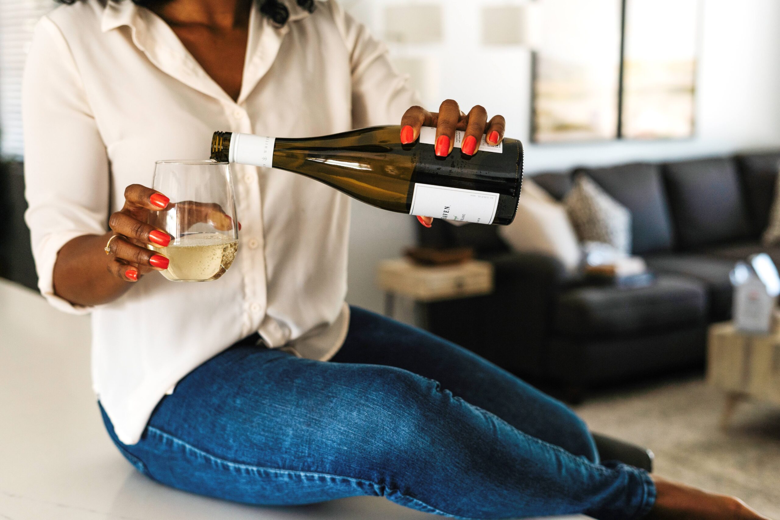black-woman-pouring-herself-a-glass-of-wine-while-sitting-on-a-table